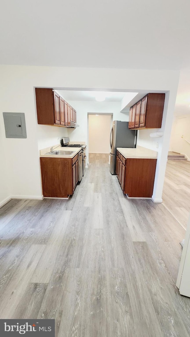 kitchen with light wood-type flooring, stainless steel appliances, and electric panel