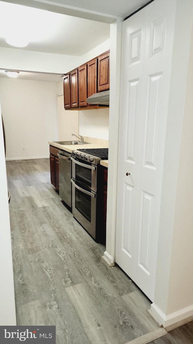 kitchen with stainless steel appliances, light hardwood / wood-style flooring, and sink