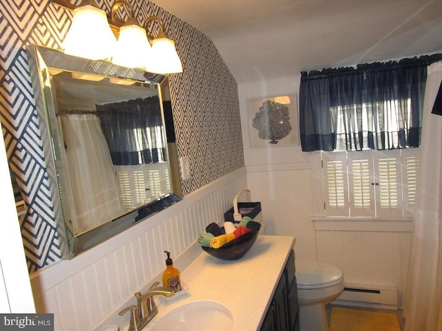 bathroom with a wealth of natural light, a baseboard heating unit, vanity, and toilet