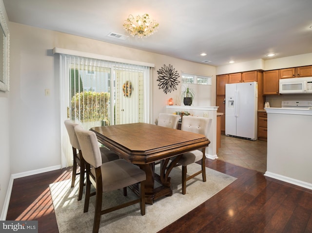 dining room with a wealth of natural light, dark hardwood / wood-style floors, and a notable chandelier