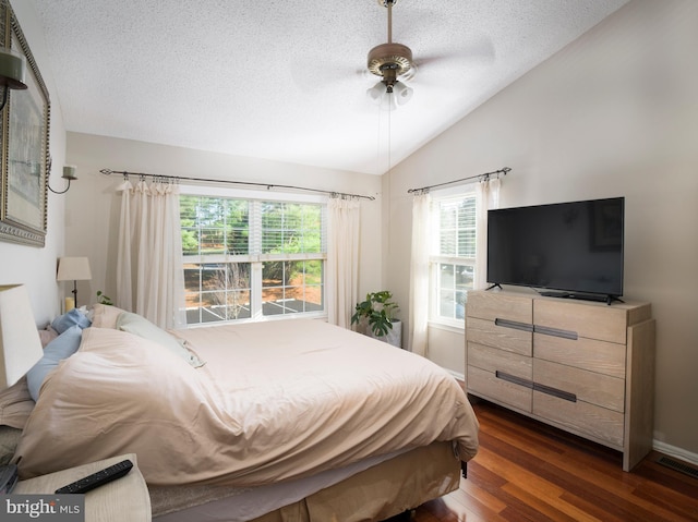 bedroom featuring ceiling fan, dark hardwood / wood-style flooring, lofted ceiling, and a textured ceiling