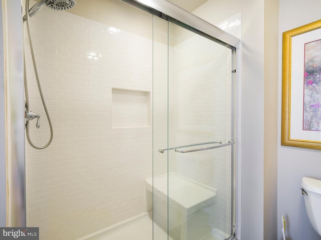 bathroom featuring toilet and a shower with shower door