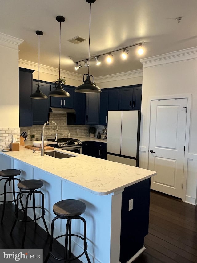 kitchen featuring pendant lighting, a kitchen breakfast bar, white refrigerator, sink, and light stone counters