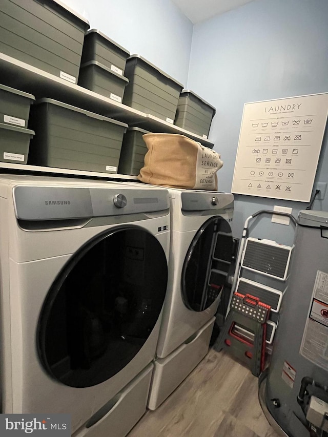 laundry room featuring washing machine and dryer, light hardwood / wood-style floors, and water heater