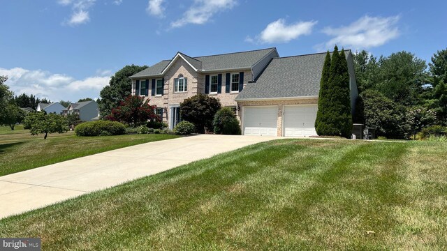 colonial inspired home featuring driveway, a front yard, a garage, and brick siding
