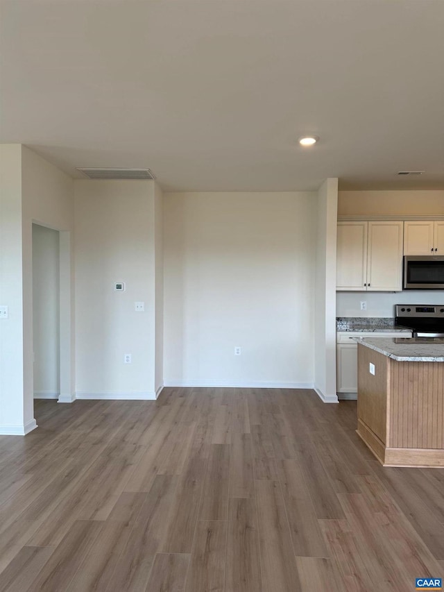 kitchen featuring appliances with stainless steel finishes, light hardwood / wood-style floors, and white cabinetry