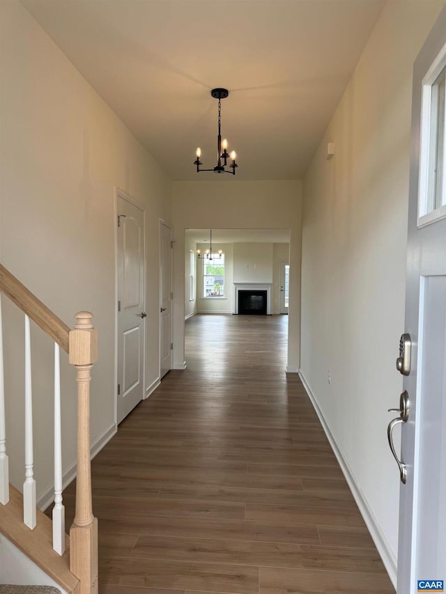 hall with dark wood-type flooring and a chandelier