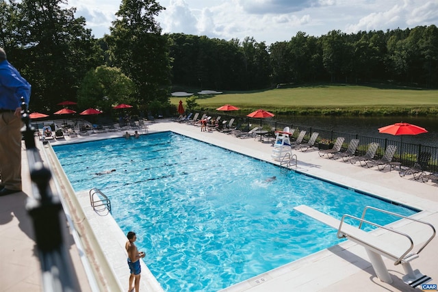 view of swimming pool featuring a diving board, a water view, and a patio