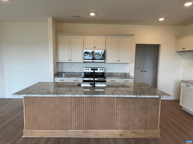 kitchen featuring dark hardwood / wood-style flooring, light stone counters, stainless steel appliances, a spacious island, and sink