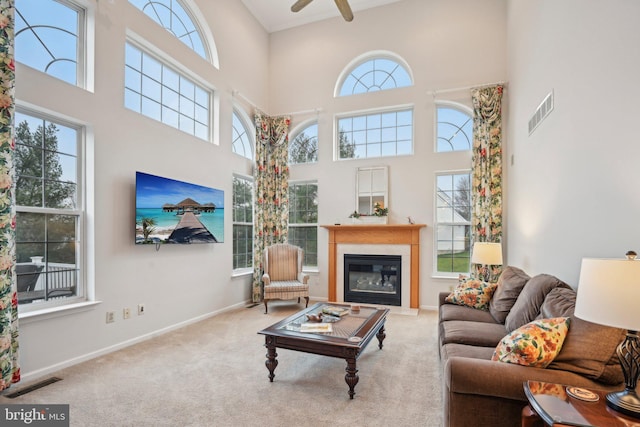 living room featuring light carpet, a towering ceiling, and ceiling fan