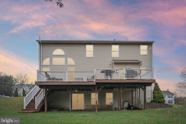 back house at dusk with a yard and a deck