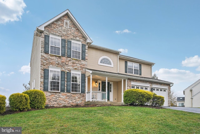 front facade featuring a garage, covered porch, and a front lawn