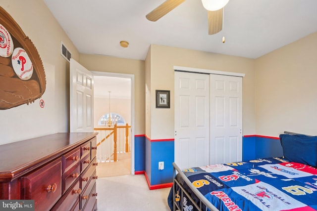 carpeted bedroom featuring ceiling fan with notable chandelier and a closet