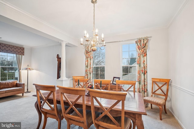 dining area with ornate columns, crown molding, carpet floors, and an inviting chandelier