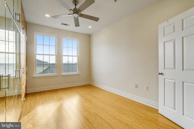 empty room featuring light wood finished floors, a ceiling fan, visible vents, and baseboards