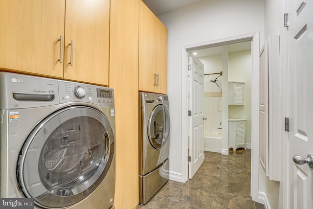 washroom with washer and dryer, cabinet space, and baseboards