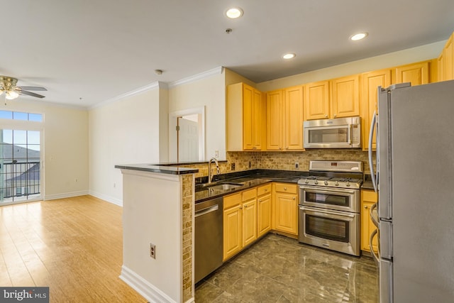 kitchen featuring dark countertops, a peninsula, a sink, stainless steel appliances, and backsplash