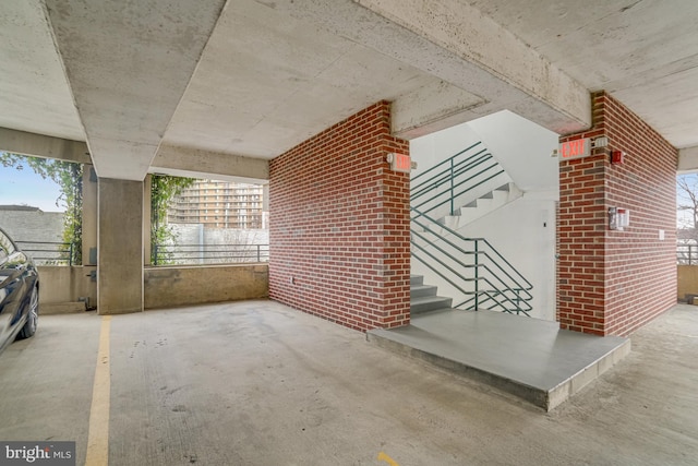 interior space featuring concrete flooring, brick wall, and stairs