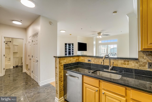 kitchen featuring dark stone counters, a sink, baseboards, decorative backsplash, and dishwasher