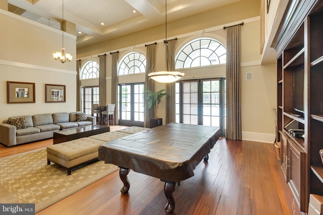 playroom with a high ceiling, wood finished floors, ornamental molding, french doors, and beamed ceiling