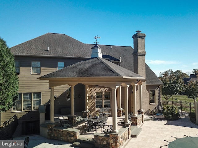 rear view of property with a pool, a patio, and a gazebo