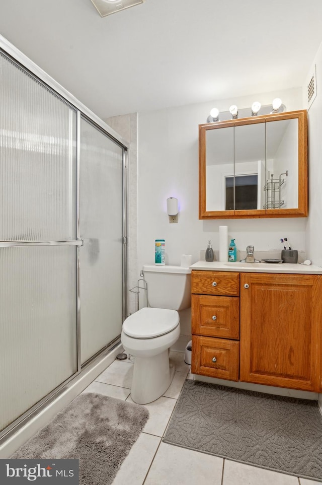 bathroom with tile patterned flooring, vanity, toilet, and a shower with door