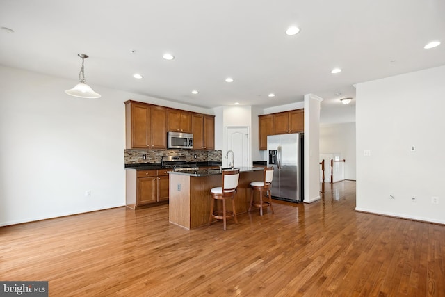 kitchen featuring sink, light hardwood / wood-style flooring, pendant lighting, a center island with sink, and appliances with stainless steel finishes