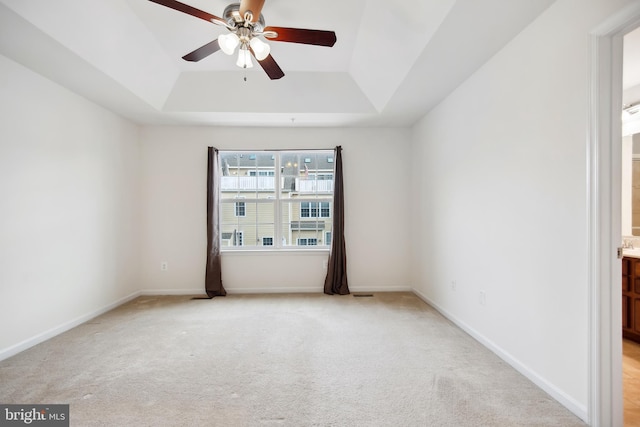 carpeted empty room featuring a raised ceiling and ceiling fan