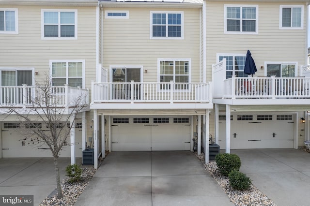 rear view of property featuring central AC unit and a garage