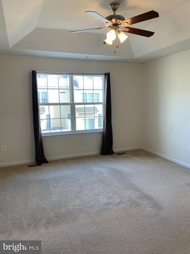 unfurnished room with a tray ceiling, ceiling fan, and light carpet