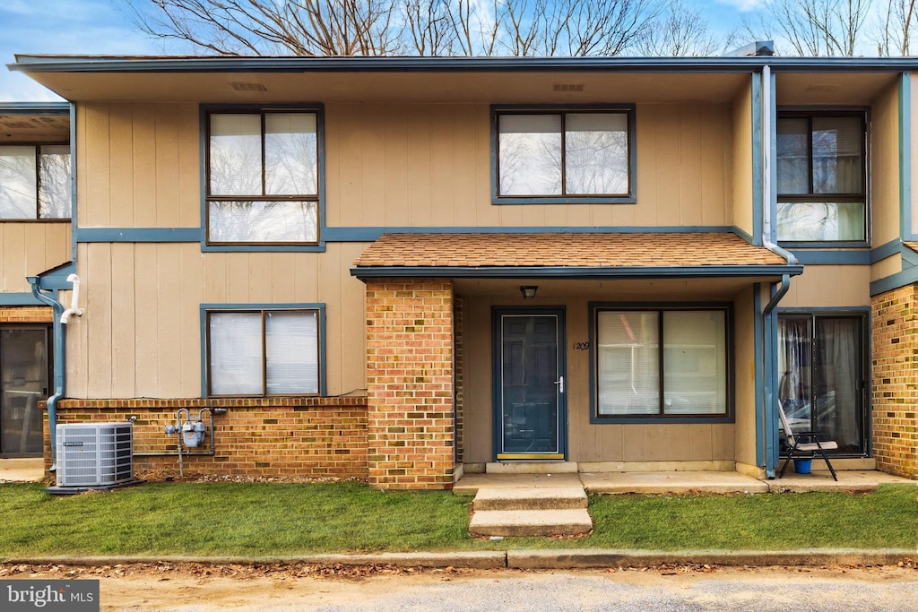 townhome / multi-family property with central AC unit and a front yard