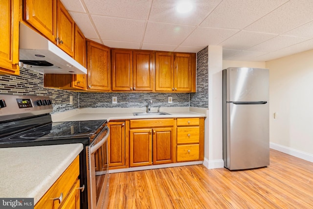 kitchen with light wood-type flooring, stainless steel appliances, tasteful backsplash, and sink