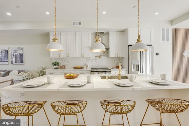 kitchen with a large island with sink, appliances with stainless steel finishes, and a breakfast bar area