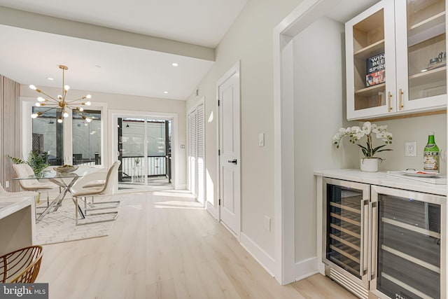 hall with a notable chandelier, wine cooler, and light hardwood / wood-style flooring