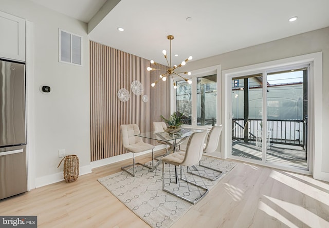 dining area with light hardwood / wood-style flooring and an inviting chandelier