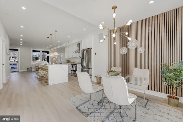 dining room with light wood-type flooring, sink, and a chandelier