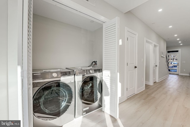 clothes washing area featuring separate washer and dryer and light hardwood / wood-style floors