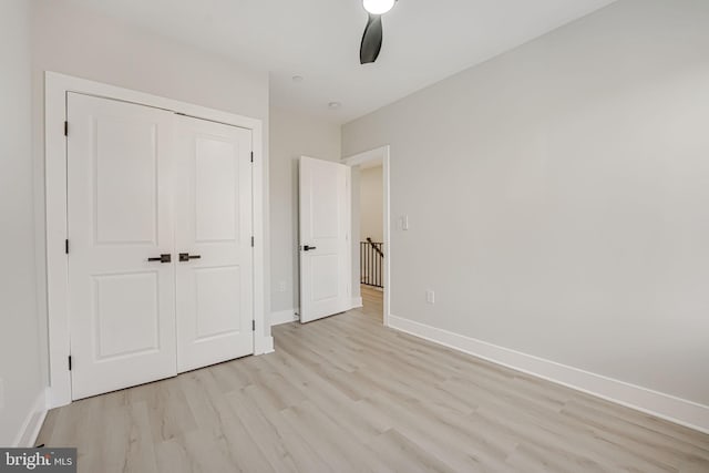 unfurnished bedroom with ceiling fan, light hardwood / wood-style flooring, and a closet