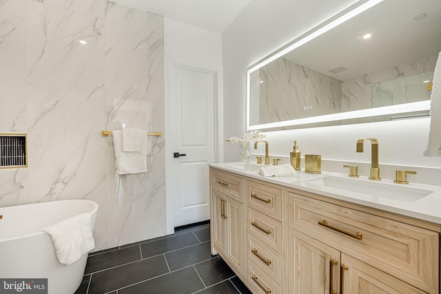 bathroom with a washtub, vanity, and tile patterned flooring