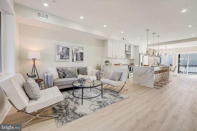 living room featuring a notable chandelier and light wood-type flooring