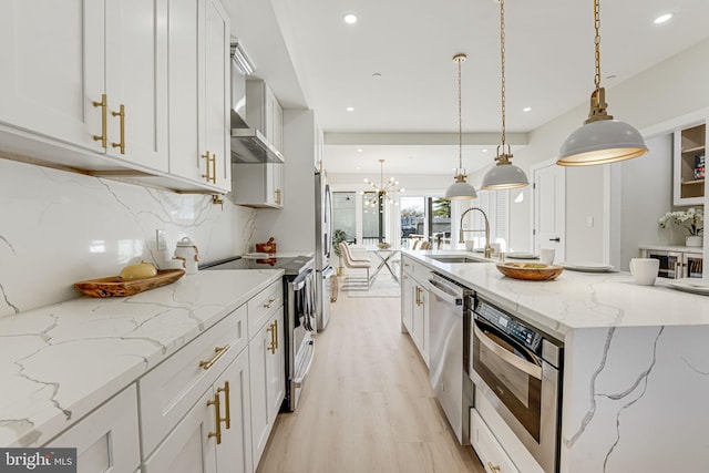 kitchen with light stone countertops, sink, hanging light fixtures, decorative backsplash, and white cabinets