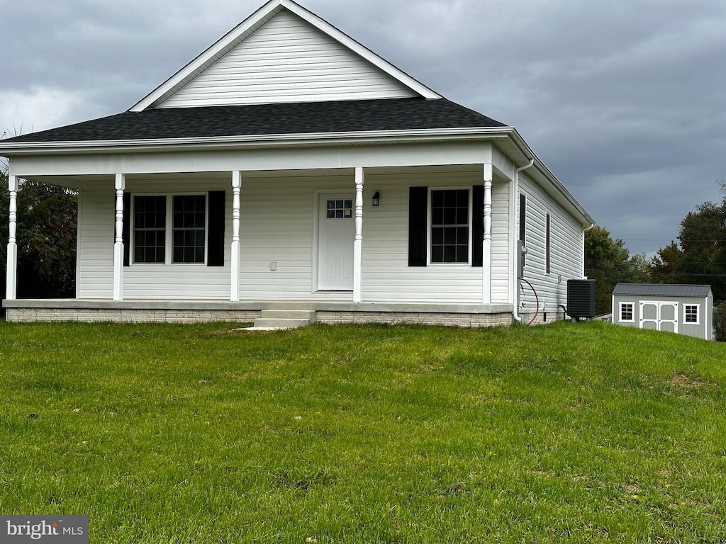 view of front of home featuring cooling unit, a shed, and a front yard