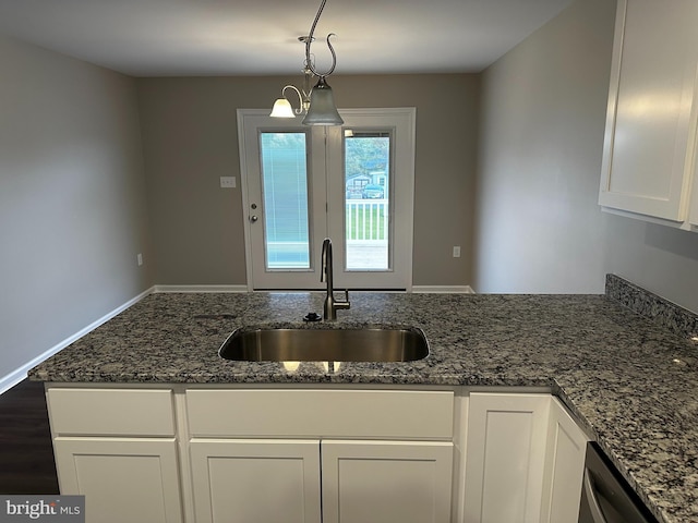 kitchen with a chandelier, hanging light fixtures, dark stone countertops, and sink