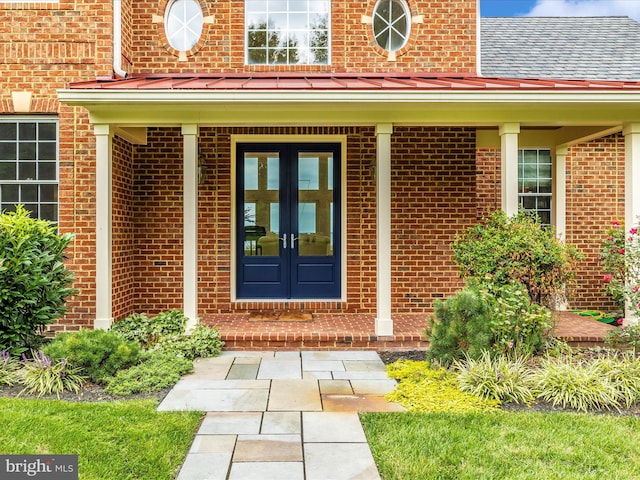 view of exterior entry with covered porch and french doors