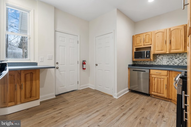 kitchen with appliances with stainless steel finishes, tasteful backsplash, and light hardwood / wood-style flooring