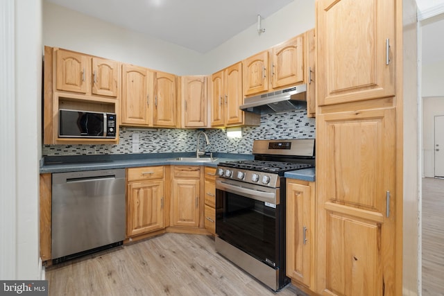 kitchen with decorative backsplash, appliances with stainless steel finishes, light brown cabinetry, sink, and light hardwood / wood-style flooring