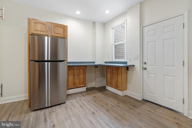 kitchen featuring stainless steel refrigerator, light brown cabinetry, and light wood-type flooring