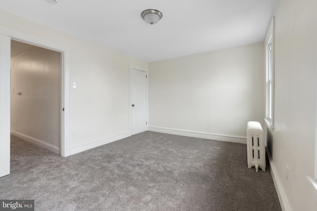 spare room with radiator heating unit and carpet