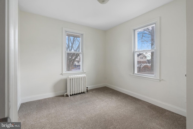 spare room with radiator heating unit and carpet floors