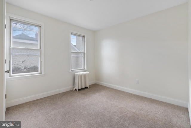 spare room with carpet, radiator heating unit, and a healthy amount of sunlight